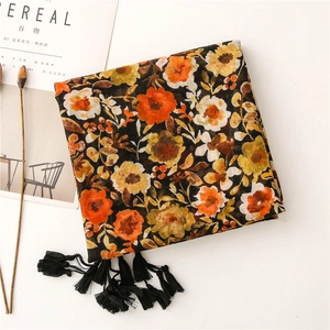 Detail of vintage floral cotton scarf with warm orange flowers and soft black tassel edges