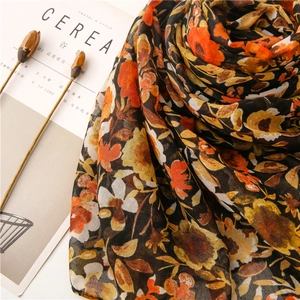 Close-up of lightweight floral scarf with retro orange and brown prints on soft fabric