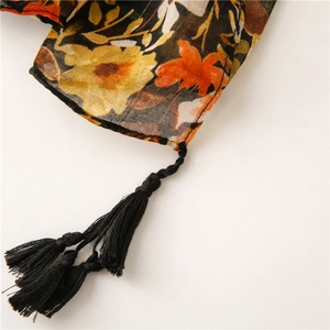 Detail of dark floral cotton-linen scarf featuring yellow flowers and black tassels