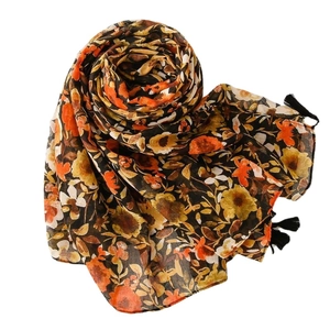 Floral cotton linen scarf with orange flower print and black tassels on a white background