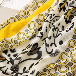 Detailed macro view of soft cotton-linen scarf with yellow geometric and floral patterns