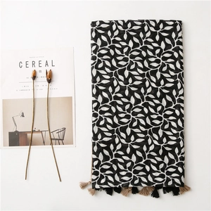Detail of soft cotton linen scarf with black and white leaf prints and fringe tassels