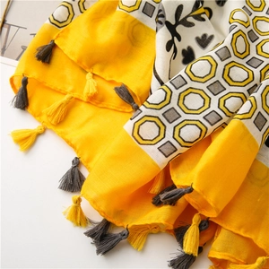 Detailed close-up of bohemian linen scarf with hexagon floral patterns and tassels