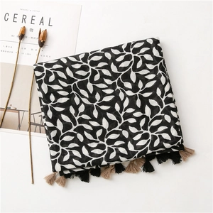 Detail of soft cotton scarf with black and white leaf prints and two-tone tassels