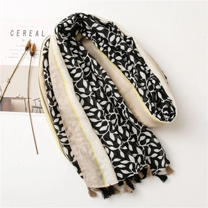 Close-up of black and white grape leaf print scarf with colorful tassels and soft texture
