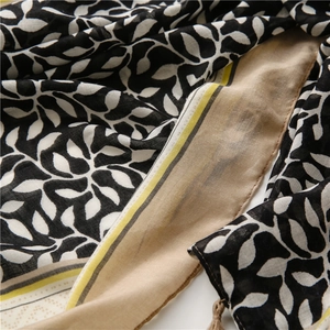 Detail of soft linen scarf with black and white leaf print and yellow fringe tassels