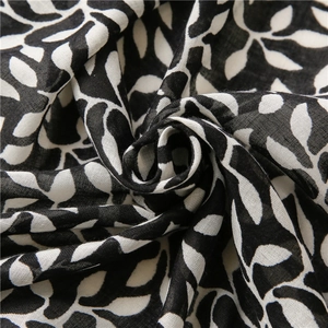 Detail of soft linen scarf featuring black and white leaf print and fine fabric texture