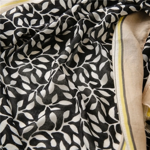 Detail of lightweight cotton linen scarf showing black and white leaf print and yellow stripes