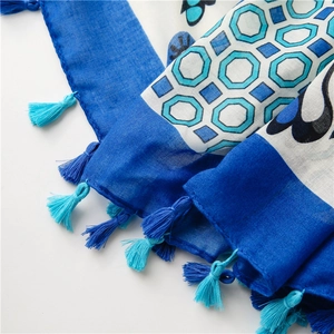 Detail of blue cotton linen scarf featuring butterfly patterns and turquoise tassels