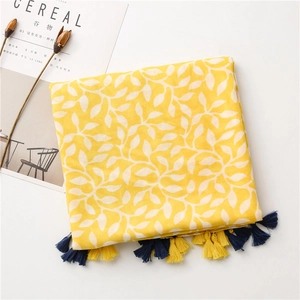 Detail of yellow cotton scarf with white leaf patterns and two-tone decorative tassels