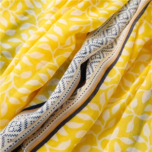 Detail of soft yellow cotton scarf featuring white leaf prints and blue polka dot borders