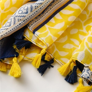 Detail of yellow cotton linen scarf with leaf print and blue tassel trim design