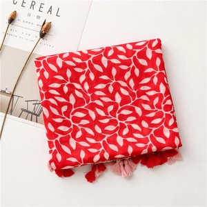 Close-up of red cotton scarf with white leaf patterns and soft fringe tassels