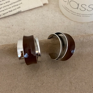 Close-up of retro C-shape silver earrings with dark brown enamel on vintage paper