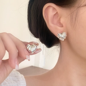 Elegant silver heart earrings with radial pleated texture shown in a lifestyle model shot