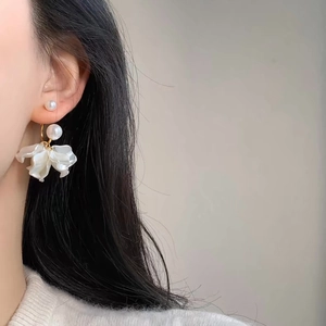 Elegant gold earrings with double pearls and white acrylic flower petals on model