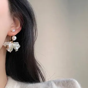 Elegant pearl flower earrings with white petals on Asian female model, French vintage style