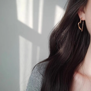 Boucles d'oreilles créoles cœur dorées minimalistes portées par un mannequin chic