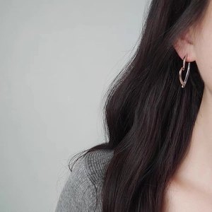 Puce d'oreille cœur argentée minimaliste portée par un mannequin en vue de profil élégante
