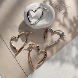 Boucles d'oreilles créoles cœur dorées et argentées sur fond de pierre texturée