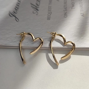 Détail de boucles d'oreilles cœurs dorées avec un design minimaliste et épuré