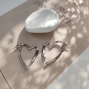 Gros plan de boucles d'oreilles en forme de cœur argenté creux avec fini poli miroir