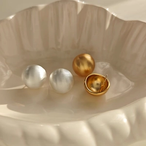 Minimalist brushed metal ball earrings set in matte gold and silver finishes