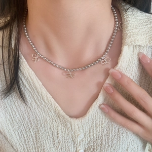 Collier à perles argentées avec quatre pendentifs nœuds minimalistes porté