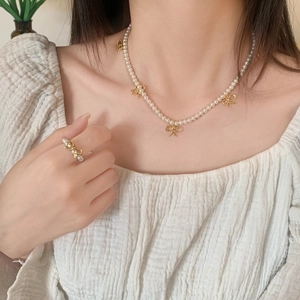 Détail de l'ensemble collier et bague en perles avec accents de nœuds dorés élégants