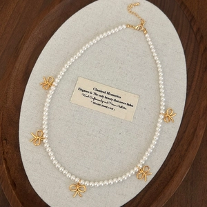 Vue détaillée du collier de perles avec cinq nœuds dorés et fermoir réglable en métal
