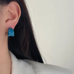 Minimalist blue enamel curved hoop earrings worn by a model in a modern stylish look