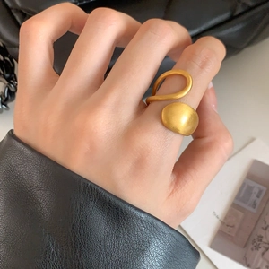 Bague asymétrique minimaliste en or mat avec arc épuré et design géométrique