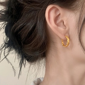Elegant gold twisted rope hoop earring with matte finish worn by a model in profile view
