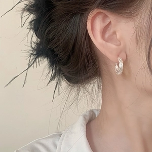 Silver twisted rope hoop earrings on female model with minimalist aesthetic and elegant style