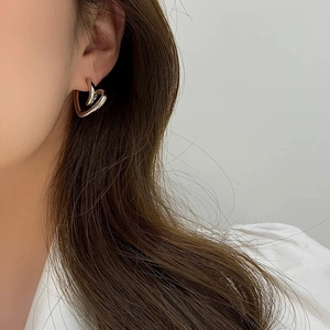 Close-up of minimalist silver heart earrings showing sleek metal finish and layered design