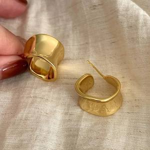 Detail showing gold C-shape earrings with mixed polished and brushed metal textures