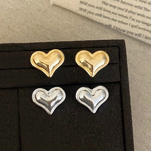 Minimalist gold and silver 3D heart stud earrings set displayed in a black velvet jewelry box
