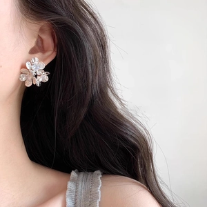 Elegant silver flower stud earrings with zircon center on model showing 45-degree angle