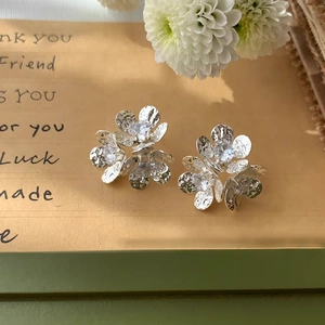 Elegant floral stud earrings with hammered petals and zircon insets on a vintage card