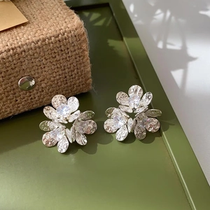 Close-up of silver flower stud earrings with hammered metal texture and zircon center