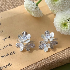 Detailed macro shot of silver flower earrings with zircon center and hammered texture petals