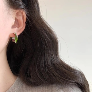 Close-up of a silver Mobius earring with green enamel finish worn by a model
