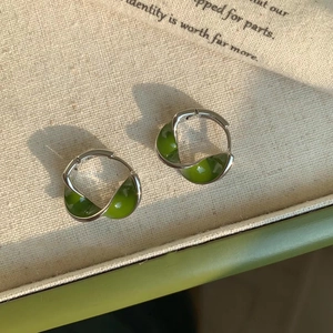 Detail of twisted Mobius silver earrings with translucent emerald green resin inlay