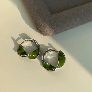 Minimalist Mobius twist silver earrings with deep green enamel finish in natural light