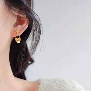 Elegant gold bow earrings with shimmering layered metal sequins on a female model