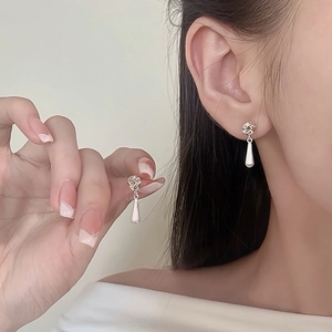Elegant silver teardrop tassel earrings with twisted knot design on model's ear