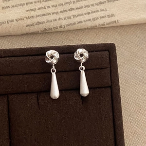 Detailed view of silver knot earrings with frosted teardrop tassels on velvet display