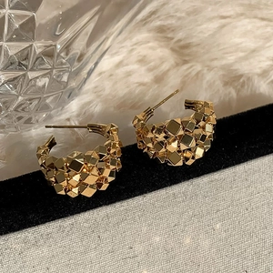 Detail of gold geometric C-shaped earrings with textured multi-layered block design
