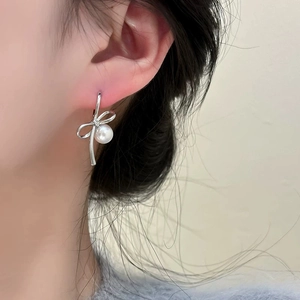 Close-up of elegant bow pearl earring on model showcasing refined metallic texture