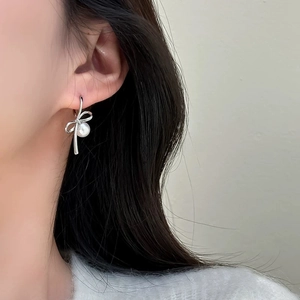 Close-up of elegant silver bow pearl earrings worn on a model for a stylish look